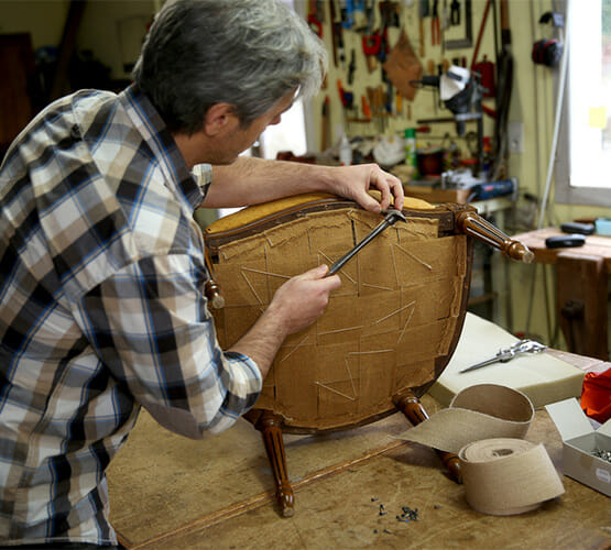 A man upholstering a chair